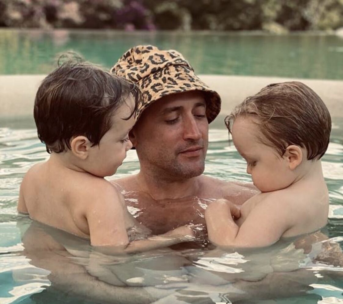 Paulo Gustavo segurando os dois filhos na piscina
